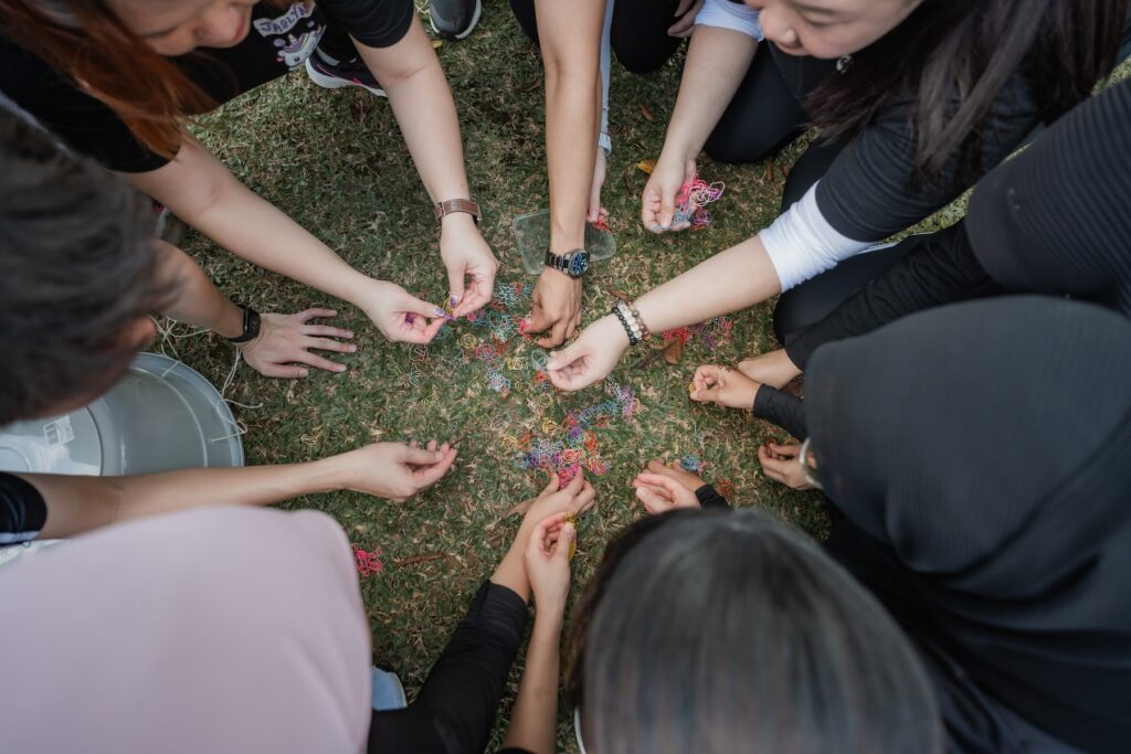 Participants placing their hands together in a circle during an outdoor team building exercise